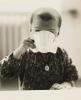 Schwarz-weiß Fotografie eines jungen Mädchens, das aus einer Tasse trinkt.