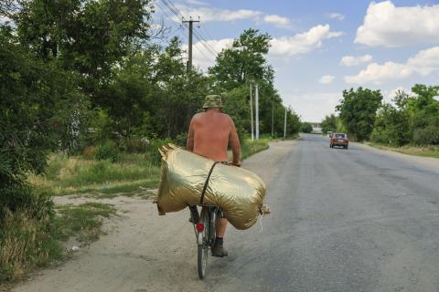 Mann transportiert einen sehr großen goldenen Sack auf dem Gepäckträger seines Fahrrades