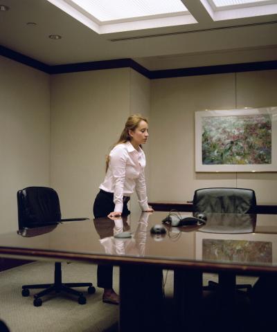 Frau stützt sich auf Tisch in Konferenzraum auf