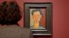 Ein Kopf ist vor einem Porträt von Modigliani und Bild das Werk an.