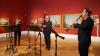 Drei Musiker stehen miihren Blasinsturmenten vor Gemälden der italienischen Malerei und musizieren.